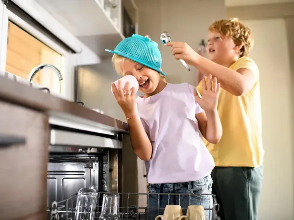 Les enfants débarrassent le lave-vaisselle du mobile home Roan Supreme avec 2 salles de bain.