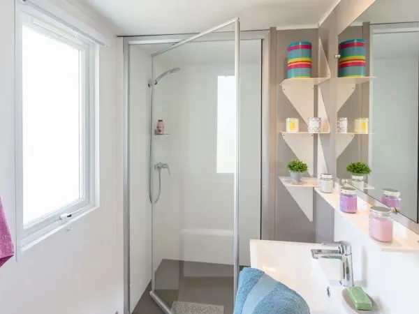 La salle de bain Roan Premium Compact est équipée d'une cabine de douche et d'un lavabo avec armoire.