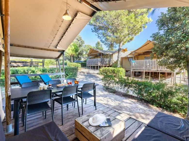 Le Roan Lodgetent Premium dispose d'une spacieuse véranda couverte avec un coin salon et une table à manger.