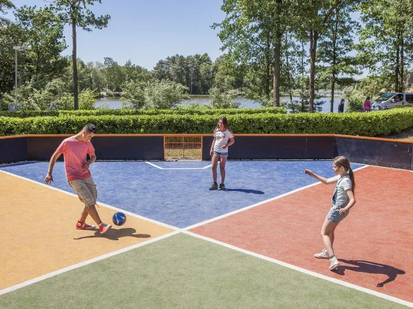 Jouer au football sur le terrain de sport du camping Roan De Schatberg.