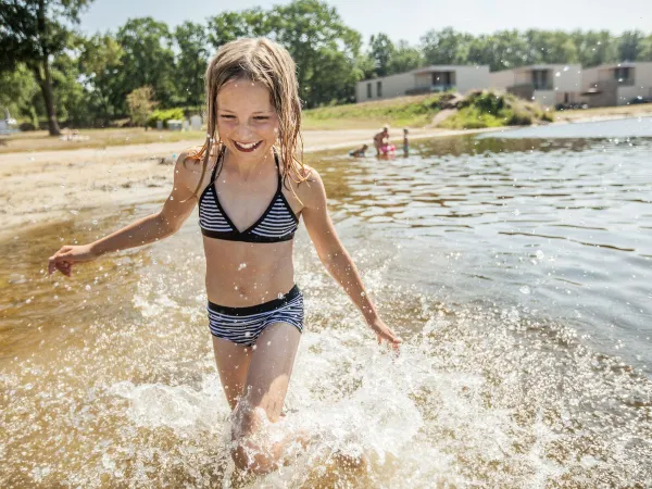 Une jeune fille se promène dans une piscine naturelle au camping Roan De Schatberg.