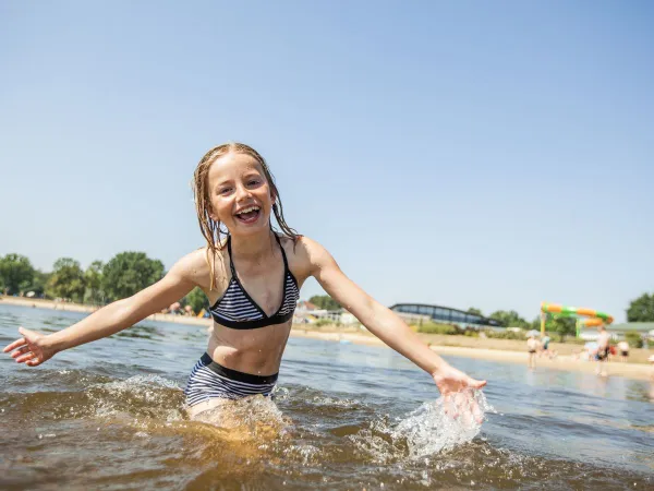 Une fille nage dans une piscine naturelle au Roan Luxury Camping De Schatberg.