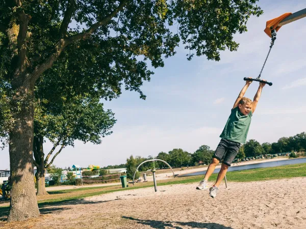 Enfant se balançant sur une corde dans l'aire de jeux du camping Roan de Schatberg.