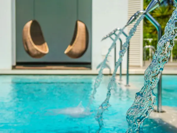 Chaises suspendues au bord d'une piscine au camping de Roan Union Lido.