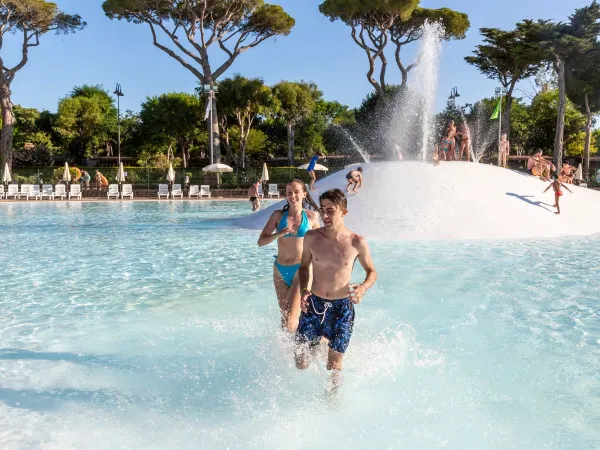 Les enfants courent dans la piscine lagunaire du camping Roan Park Albatros.