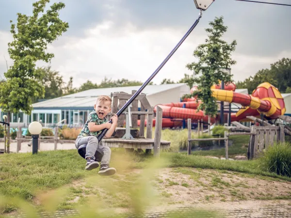 S'amuser dans l'aire de jeux, glisser sur le téléphérique du camping Roan Ackersate.