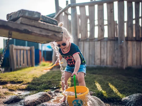 Enfant jouant avec l'eau dans la cascade du camping Roan Ackersate.