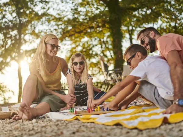 Une famille joue à un jeu de société au camping Roan Zelena Laguna.