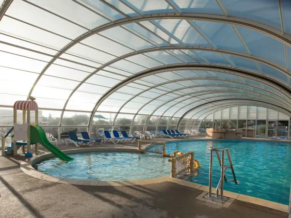 Piscine couverte avec toboggan aquatique au camping Roan Le Domaine de Beaulieu.