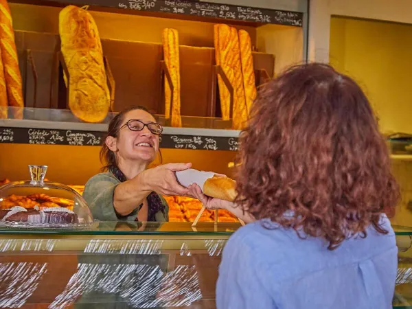 Une dame va chercher des baguettes à la boulangerie du Roan camping Les Dunes.