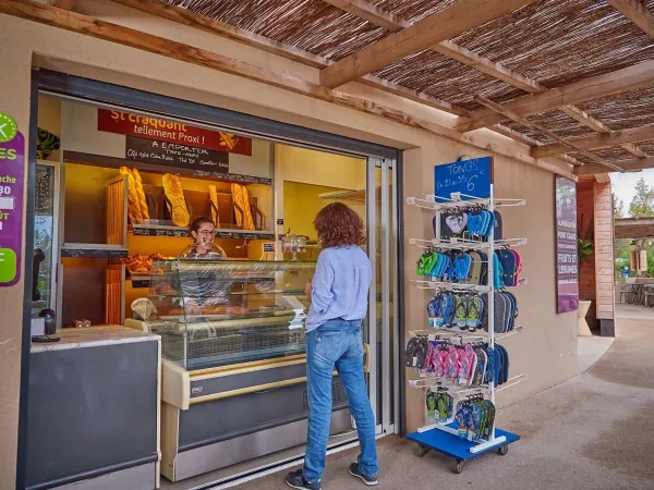 Les clients prennent une baguette fraîche à la boulangerie du camping Roan Les Dunes.