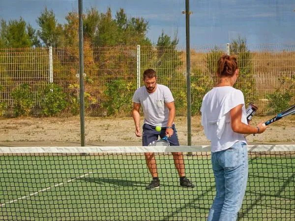 2 personnes font une partie de tennis au camping Roan Les Dunes.