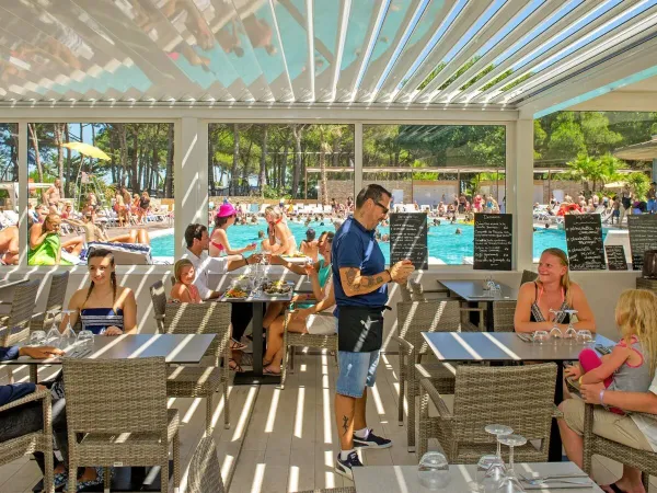 Une terrasse complète au bord de la piscine du camping Roan Le Castellas.