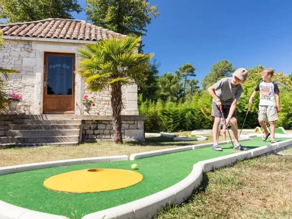 Les enfants jouent au mini-golf au camping Roan La Clairière