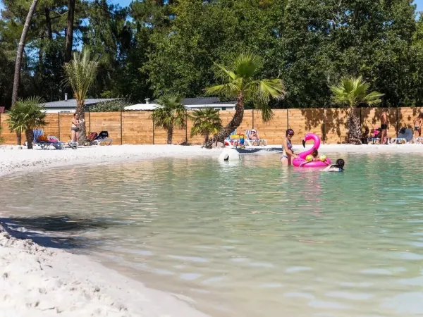 Personnes prenant un bain de soleil au bord de la piscine du camping Roan La Clairière.