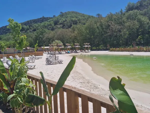 Piscine lagon avec plage de sable et transats au camping Roan Verdon Parc.