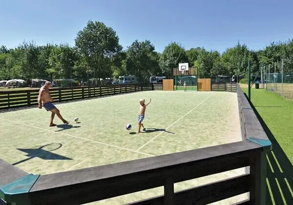 Un père et son fils jouent au football sur le terrain du camping Roan Domaine de La Brèche.