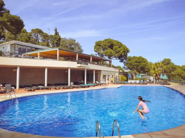 Une jeune fille saute dans la piscine du camping Roan Internacional de Calonge.