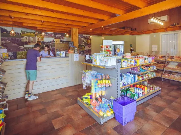 Un client est expliqué à la réception/boutique du camping Roan 't Veld.