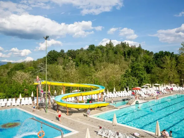 Terrasse ensoleillée avec piscine semi-olympique et toboggan au camping Roan hu Norcenni Girasole village.