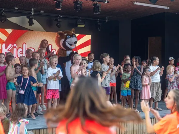Enfants chantant joyeusement sur la scène du camping Roan Château de Fonrives.