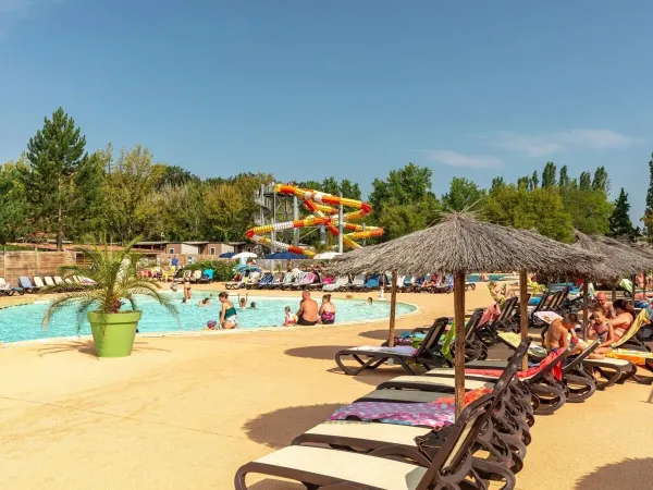 Chaises longues au bord de la piscine du camping Roan Château de Fonrives.