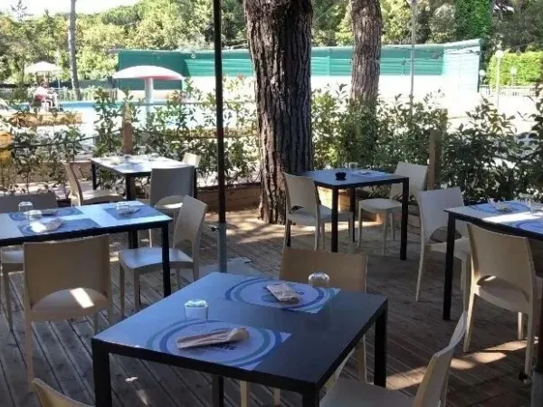 Terrasse ombragée au bord de la piscine du camping Roan Del Forte.