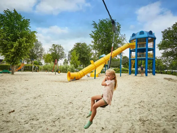 Fille sur le téléphérique dans la grande aire de jeux du camping Roan Terspegelt.