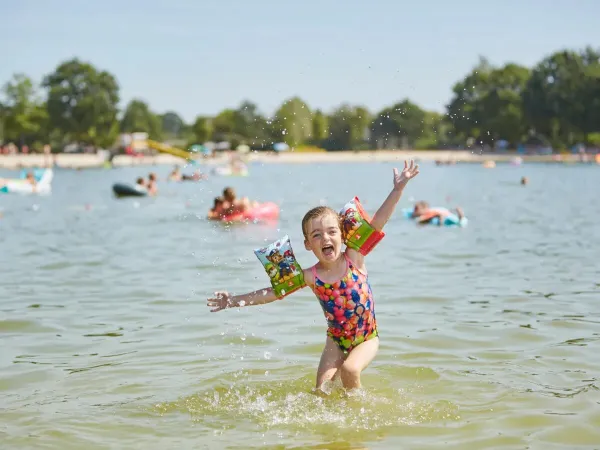 Jeune fille heureuse dans la piscine du camping Roan Terspegelt.