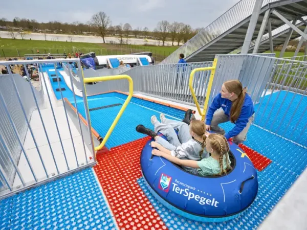 Les enfants glissent sur le TubbytJump du camping Roan Terspegelt à l'aide d'un pneu.