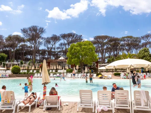 Des personnes s'amusent au bord de la piscine lagunaire du camping Roan hu Fabulous village.