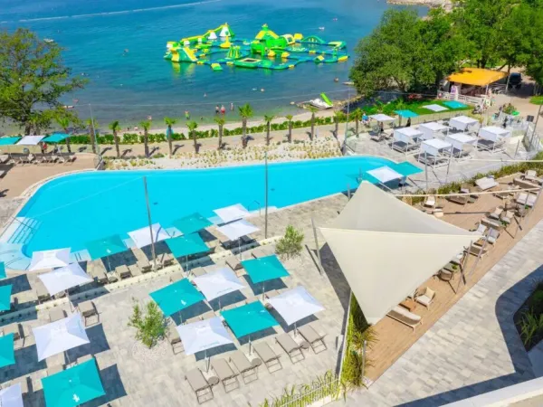 Vue d'ensemble de la plage de galets et de la piscine du camping Roan Bijela Uvala.