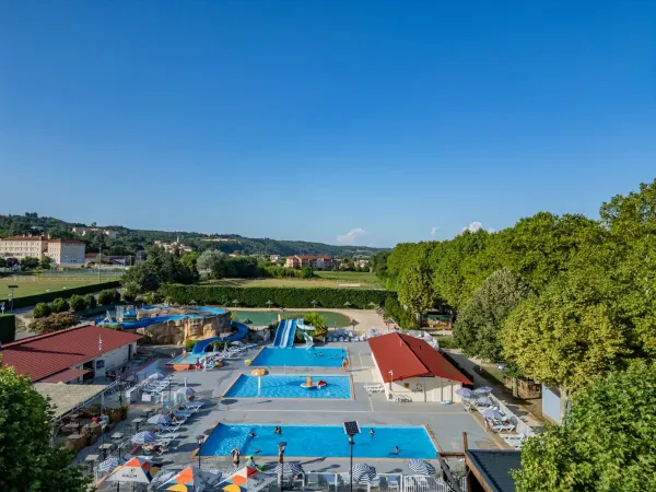 La piscine avec toboggans et la terrasse adjacente au camping Roan Château de Galaure.