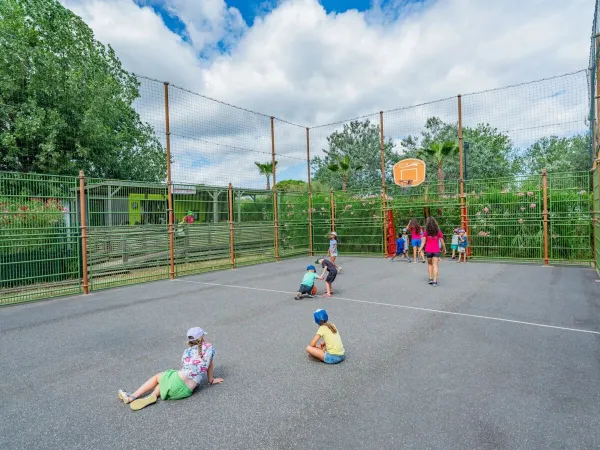 Les enfants jouent sur le terrain de sport polyvalent du camping Roan Les Méditerranées Beach Garden.