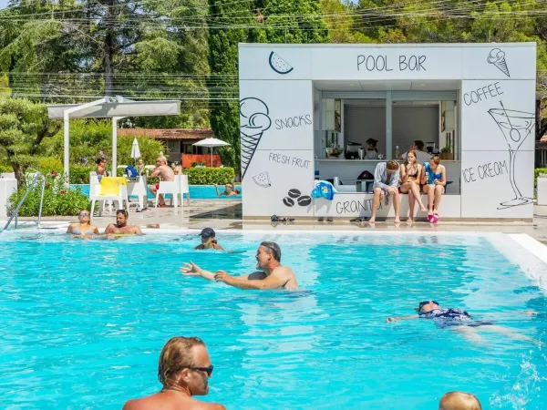 Des personnes se baignent et se détendent au bar de la piscine du camping Roan Valkanela.