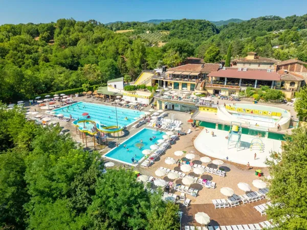 Terrasse ensoleillée avec piscine semi-olympique et toboggan au camping Roan hu Norcenni Girasole village.