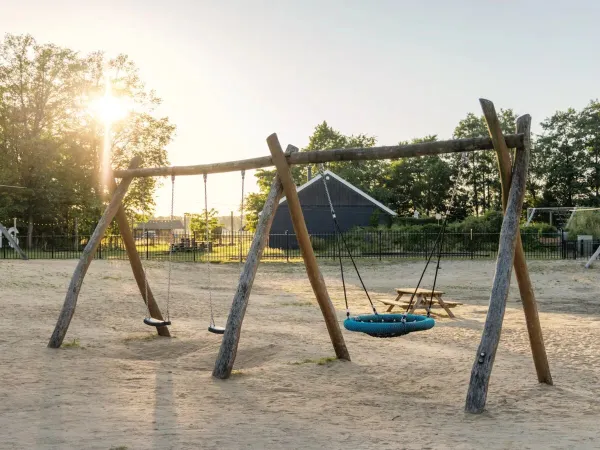 Le terrain de jeu en sable avec des balançoires au camping Roan de Twee Bruggen.