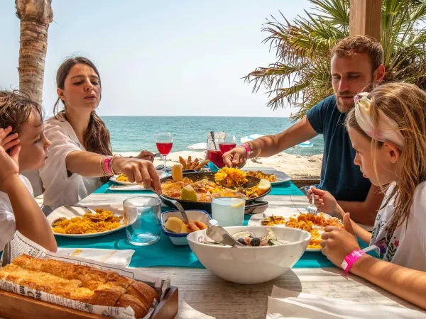 Une famille mange sur la plage du camping Roan Alannia Els Prats.