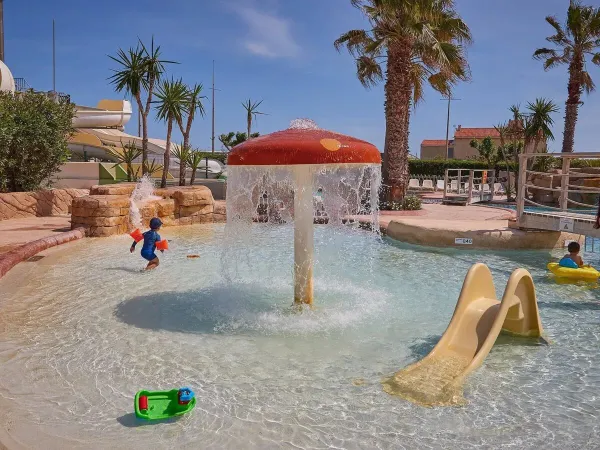 Piscine pour enfants avec toboggan et arroseur de champignons au camping Roan Le Petit Mousse.
