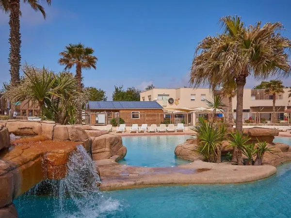 Belle plantation au bord de la piscine avec cascade au camping Roan Le Petit Mousse.