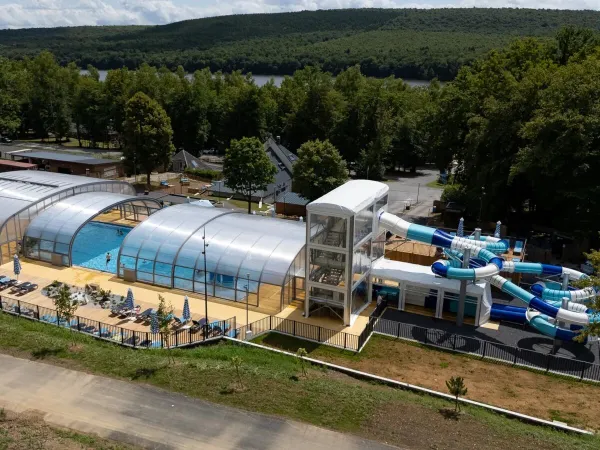 Vue d'ensemble de la piscine avec toboggans et chaises longues au camping Roan Le Lac des Vieilles Forges.
