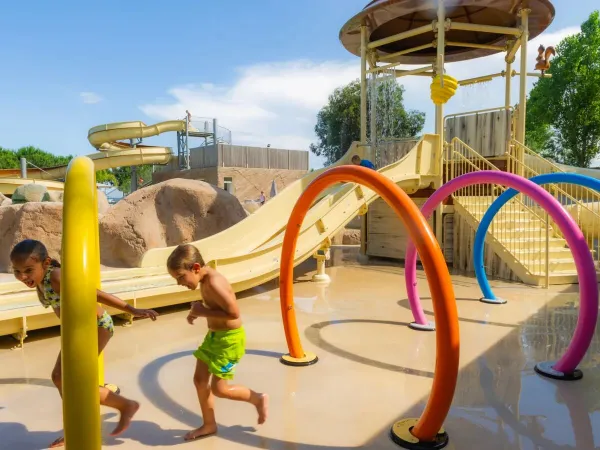 Des enfants courent dans les arroseurs du camping Roan Arinella Bianca.