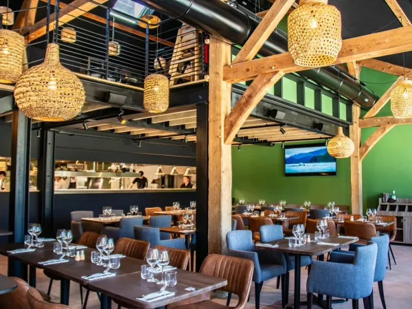 Restaurant d'ambiance avec cuisine ouverte au camping Roan Domaine des Ormes.