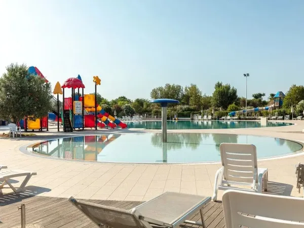 Piscine avec chaises longues et aire de jeux au camping de Vigna sul Mar.