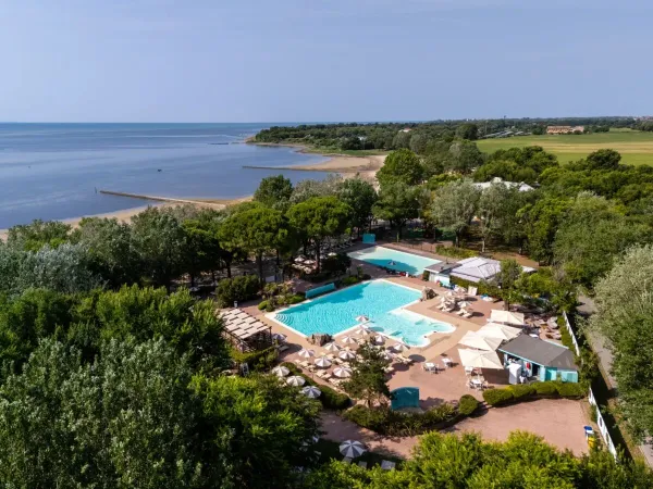 Vue d'ensemble de la piscine et de la plage du camping de Roan Tenuta Primero.