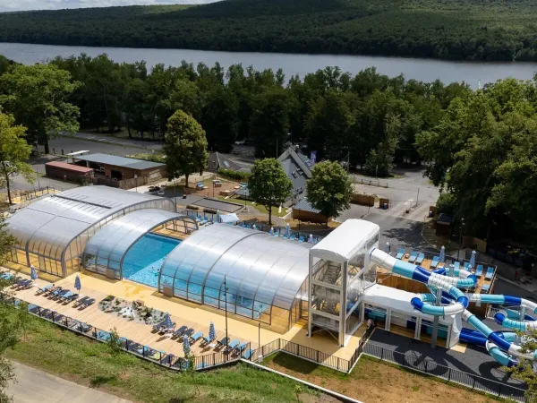 Vue d'ensemble de la piscine avec toboggans et chaises longues au camping Roan Le Lac des Vieilles Forges.
