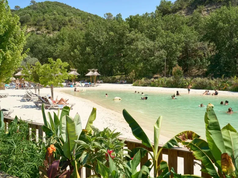 Piscine lagon avec plage de sable et transats au camping Roan Verdon Parc.
