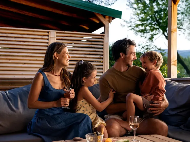 Père et enfants s'amusant sur le canapé du mobil-home du camping de Roan Le Petit Mousse.