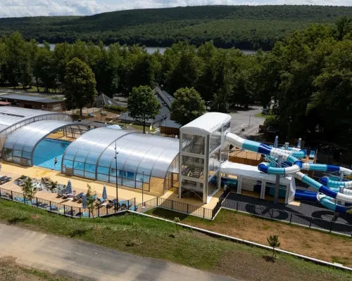 Vue d'ensemble de la piscine avec toboggans et chaises longues au camping Roan Le Lac des Vieilles Forges.