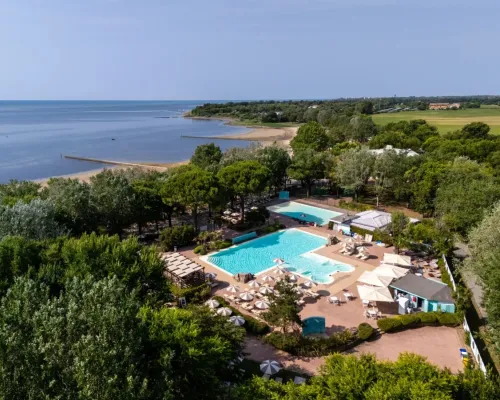 Vue d'ensemble de la piscine et de la plage du camping de Roan Tenuta Primero.